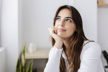 Thoughtful smiling woman with hand on chin at home - XLGF03105