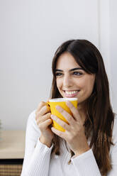 Smiling woman holding coffee cup at home - XLGF03113