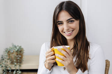 Happy woman holding coffee cup at home - XLGF03114