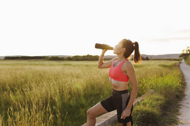 Woman drinking water from bottle on sunny day - EGHF00600