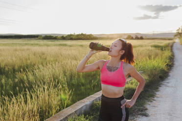 Woman drinking water from bottle on sunny day - EGHF00606