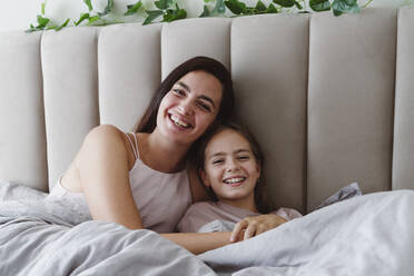 Happy mother and daughter relaxing on bed - OSF01085
