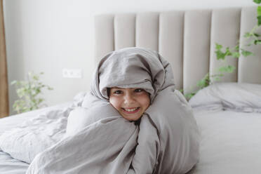 Glückliches Mädchen in Decke eingewickelt auf dem Bett zu Hause - OSF01089