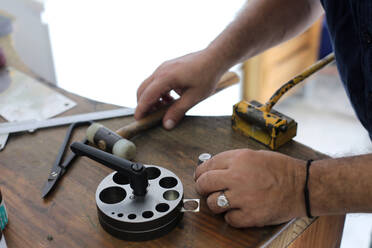 Schmuckkünstlerin bei der Verwendung eines Werkzeugs auf der Werkbank in der Werkstatt - RFTF00316
