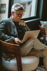 Businessman looking busy working on laptop. Thoughtful business professional reading emails on laptop in office lobby. - JLPSF13884