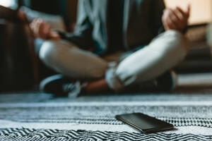 Handy auf dem Boden mit einem Geschäftsmann meditiert in Yoga-Pose im Büro. Mann macht Yoga-Meditation im Büro Lounge. - JLPSF13892