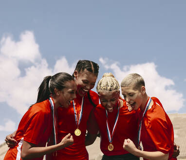 Aufgeregte Fußballspielerinnen, die nach dem Gewinn der Meisterschaft vor Freude jubeln. Frauenfußballmannschaft mit Medaillen bei der Siegesfeier. - JLPSF13922