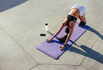 Fitness-Frau übt Yoga am Morgen. Junge Frau in Sportkleidung macht Stretching-Workout im Freien. Downward facing dog yoga pose. - JLPSF13969