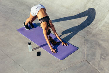 Fitness-Frau, die die Yoga-Pose des nach unten gerichteten Hundes übt. Frau in Sportkleidung beim Stretching-Workout im Freien. - JLPSF13970