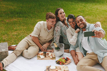 Gruppe von glücklichen Freunden, die zusammen Spaß haben und ein Selfie mit dem Handy machen. Junge Leute beim Picknick, die ein Selbstporträt mit dem Smartphone machen. - JLPSF14076