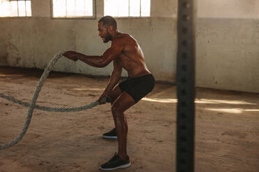 Fitness Mann Training mit Kampf Seile innerhalb verlassenen Lagerhaus. muskulösen Mann tun Kampf Seil Training. - JLPSF14133