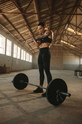 Female doing arms stretching before weight lifting working in fitness space in old factory. Woman - JLPSF14199