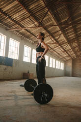 Frau ruht sich nach dem körperlichen Training in einem Cross-Trainingsraum in einer verlassenen Fabrik aus. Frau nach dem Training in einem alten Lagerhaus. - JLPSF14203