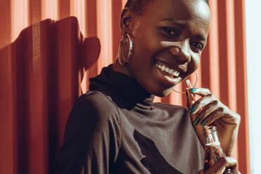 Close up of beautiful young woman standing outdoors and looking at camera while drinking cola. African woman relaxing outdoors on a summer day. - JLPSF14238