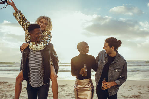 Zwei glückliche junge Männer mit ihren Freundinnen, die sich am Strand vergnügen. Gruppe von Freunden im Urlaub am Strand. - JLPSF14268