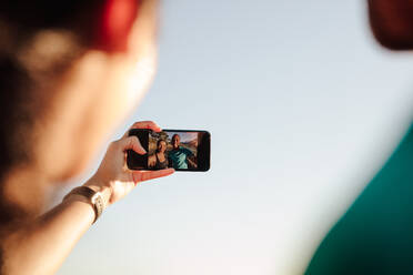 Abgeschnittene Aufnahme eines sportlichen Paares, das während des Trainings ein Selfie macht. Eine sportliche Frau macht ein Selfie mit ihrem Handy. - JLPSF14290