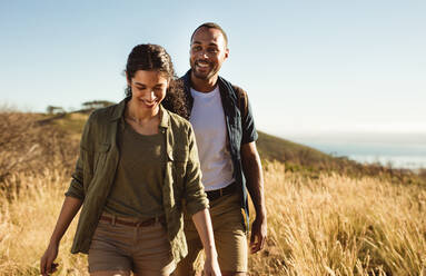 Ein Paar genießt einen Wanderausflug an einem Sommertag. Fröhliches Paar, das zusammen auf einem Hügel spazieren geht. - JLPSF14294