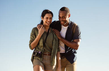 Touristenpaar, das im Freien spazieren geht und zusammen lacht. Porträt eines Paares im Urlaub, das glückliche Momente genießt. - JLPSF14300