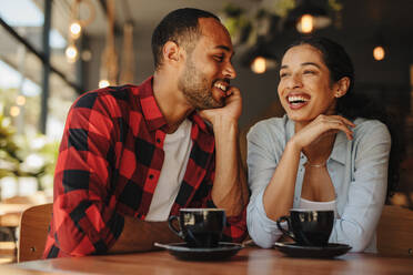 Schönes Paar sitzt zusammen im Café und lächelt. Mann und Frau sitzen im Café mit Tassen Kaffee. - JLPSF14310