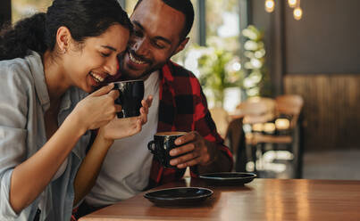 Zärtliches Paar bei einem Kaffee in einem Café. Afrikanischer Mann und Frau unterhalten sich bei einem Kaffee. - JLPSF14313