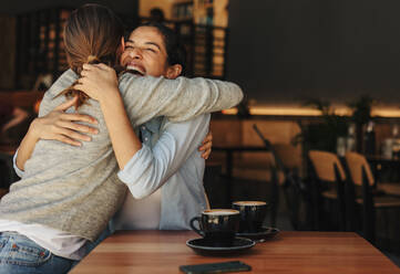 Zwei Frauen treffen sich in einem Café. Freunde umarmen sich in einem Café. - JLPSF14318