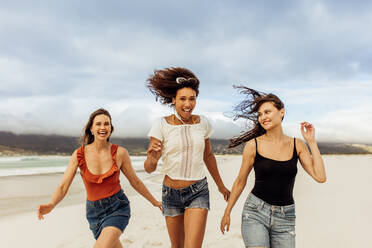 Three cheerful friends enjoying on beach. Multiethnic friends on a vacation having fun on the beach. - JLPSF14331