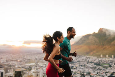 Fröhliches Athletenpaar, das gemeinsam auf der Straße läuft. Fitnesspaar, das morgens auf der Straße joggt. - JLPSF14343