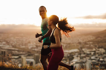 Fitness-Paar geht für Sonnenaufgang laufen. Fitness-Mann und Frau läuft auf der Straße. - JLPSF14344