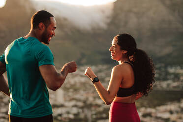 Ein Fitness-Paar gibt sich nach dem Training die Hand. Ein sportlicher Mann und eine Frau feiern nach einem Lauf. - JLPSF14348