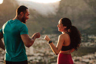 Fitness couple giving fist bump after the workout. Athletic man and woman celebrate after a run. - JLPSF14348