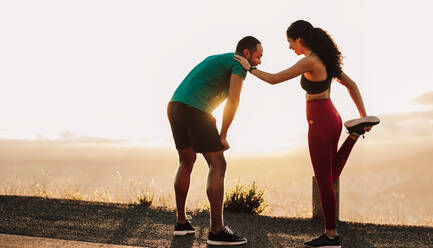 Fitness-Paar, das sich für einen Morgenlauf bereit macht. Sportlicher Mann und Frau stehen auf einer Straße und machen sich warm. - JLPSF14351