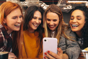 Gruppe von Frauen, die ein Selfie im Café machen. Weibliche Freunde, die ein Selfie mit einem Smartphone machen. - JLPSF14380