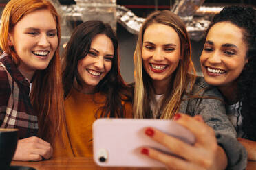 Gruppe von Frauen sitzen im Café und nehmen Selfie mit Handy. Frau sitzt mit Freunden im Café und macht ein Selfie. - JLPSF14381