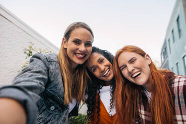 Schöne junge Frau im Gespräch Selfie mit Freunden stehen zusammen. Gruppe von Frauen in der Stadt machen ein Selbstporträt. - JLPSF14401