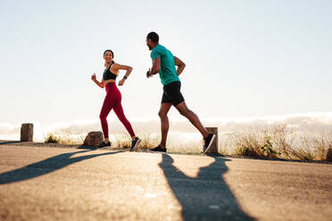 Fitness-Paar bei einem Lauf auf der Straße. Sportler, die gemeinsam für einen Marathon trainieren. - JLPSF14413