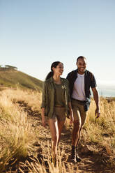 Lächelndes Paar auf einem Wanderausflug an einem sonnigen Tag. Porträt eines Paares, das gemeinsam auf einem Wanderweg spazieren geht. - JLPSF14415