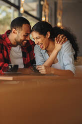 Ein Paar, das sich bei einem Date in einem Café amüsiert. Ein Mann und eine Frau unterhalten sich lächelnd in einem Café. - JLPSF14421