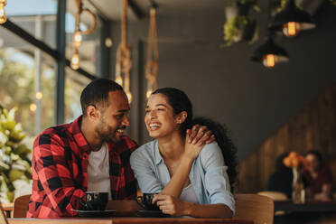 Afrikanischer Mann und Frau sitzen in einem Café und unterhalten sich bei einer Tasse Kaffee. - JLPSF14422