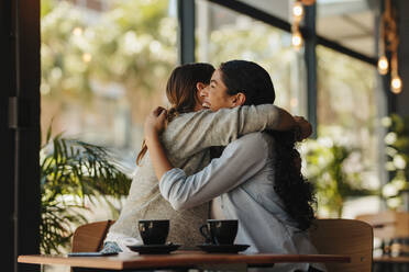 Zwei Freundinnen treffen sich in einem Café. Frauen, die zusammen in einem Café sitzen und sich umarmen. - JLPSF14430