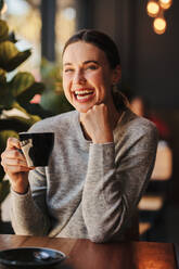 Attraktive Frau trinkt Kaffee im Café. Frau trinkt eine Tasse Kaffee und lacht im Café. - JLPSF14444