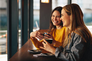 Zwei Freundinnen treffen sich am Wochenende in einem Café. Zwei Freundinnen sitzen in einem Café und trinken einen Kaffee und unterhalten sich. - JLPSF14459