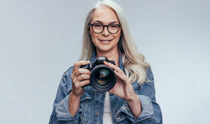 Professionelle Fotografin mit ihrer Kamera. Ältere Frau geht zu einem Fotoshooting mit professioneller Kamera. - JLPSF14511