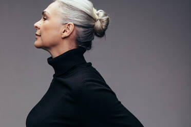 Profile view of mature woman in black casuals on grey background. Senior caucasian woman with hair bun. - JLPSF14519