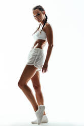 Junge Frau posiert selbstbewusst in weißer Sportkleidung. Weibliches Fitnessmodell in Sportkleidung auf weißem Hintergrund - JLPSF14588
