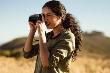 Nahaufnahme einer Frau, die mit einer Digitalkamera fotografiert. Touristin, die an einem sonnigen Tag die Natur fotografiert. - JLPSF14613