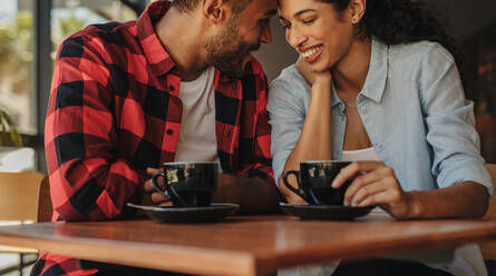 Liebender Mann und Frau sitzen in einem Café und berühren sich an der Stirn. Verliebtes Paar trifft sich in einem Café. - JLPSF14620