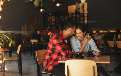 Loving couple sitting inside a cafe touching foreheads and smiling. Beautiful couple in love in a coffee shop. - JLPSF14621