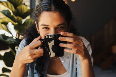 Close up of young woman drinking coffee at cafe. Female having a cup of coffee. - JLPSF14630