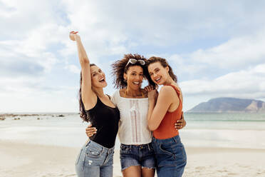 Frauen im Urlaub stehen zusammen am Strand. Lächelnde Freundinnen genießen den Urlaub am Strand. - JLPSF14635