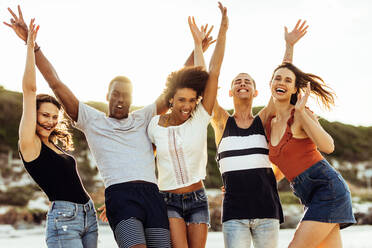 Eine multiethnische Gruppe von Freunden, die sich auf einer Strandparty amüsieren. Fröhliche Freunde, die Spaß haben, tanzen und sich gemeinsam vergnügen. - JLPSF14639